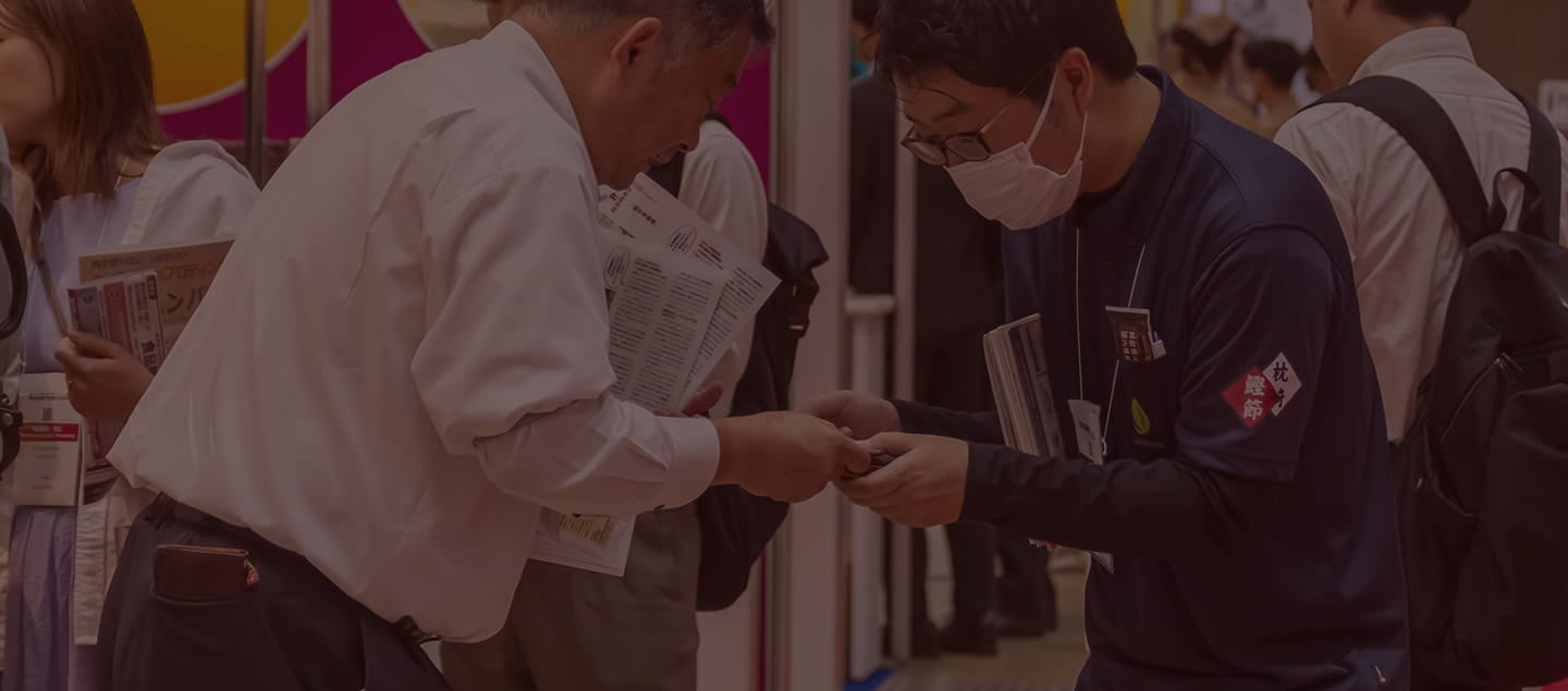 exhibitor handing over test sample to visitor at Hi Japan