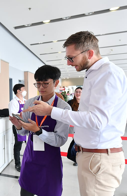 Exhibitor and visitors chatting whilst looking at a phone