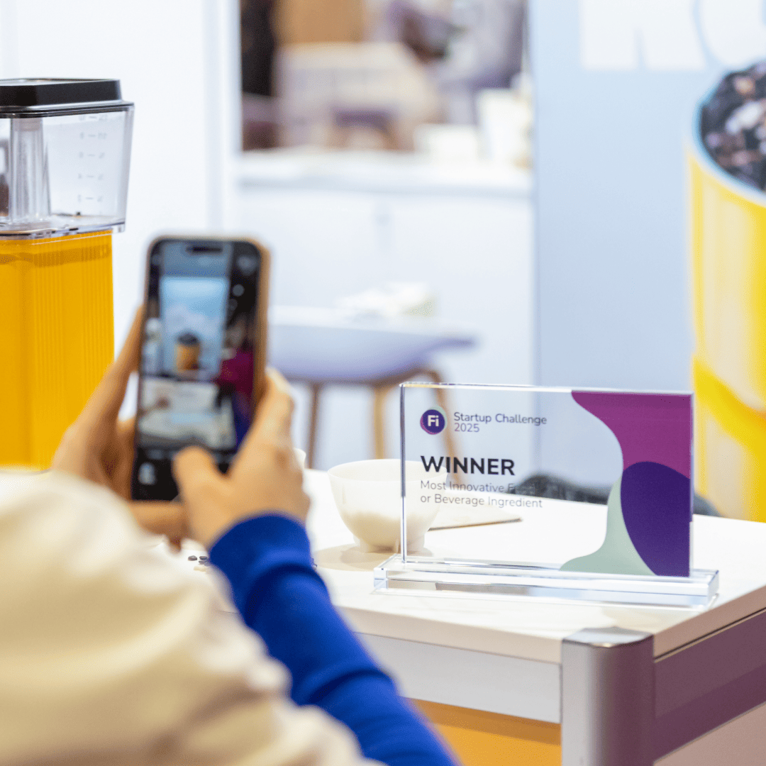 Visitor holding up sticker near signage at Fi Europe